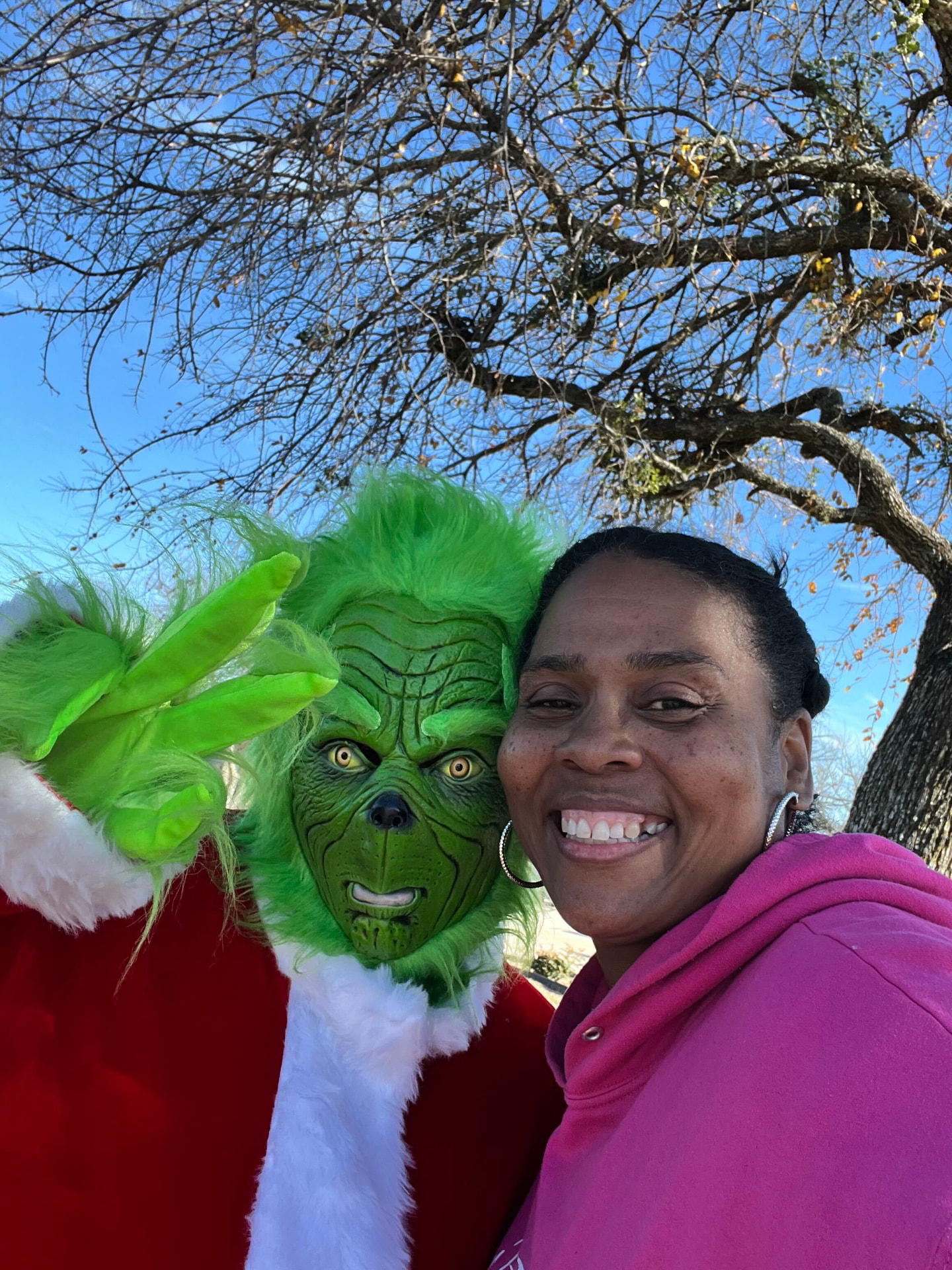 Tara smiling beside the Grinch at the 2025 holiday event