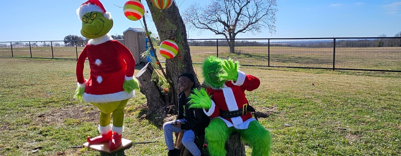A young guest waving with the Grinch at the 2025 holiday event